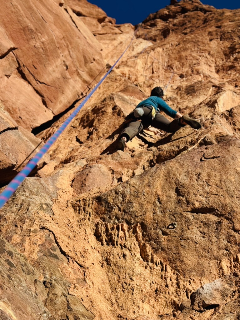 Climber on a sandstone route on a bluebird day